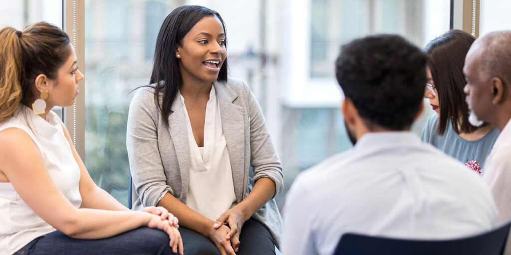 woman sitting in a group therapy circle and talking cheerfully