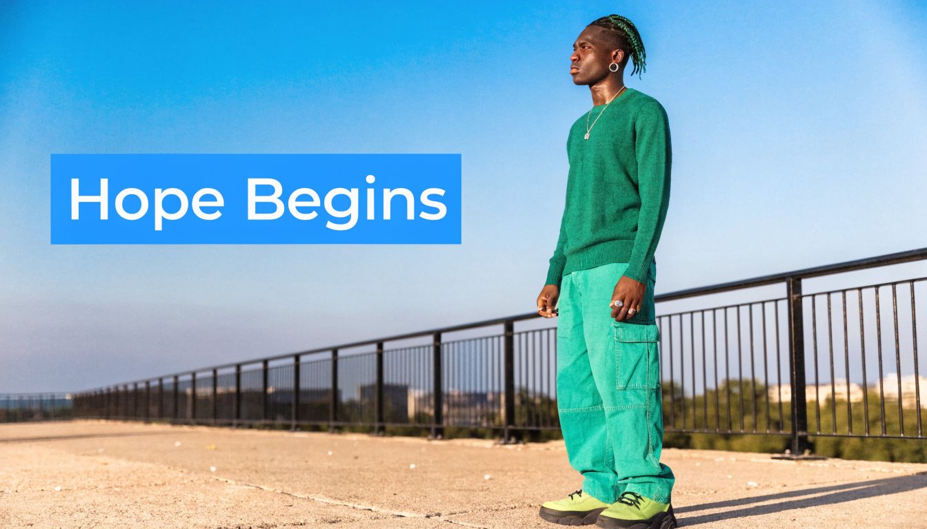 A young man wearing a green sweater and pants stands on a rooftop looking toward the horizon.