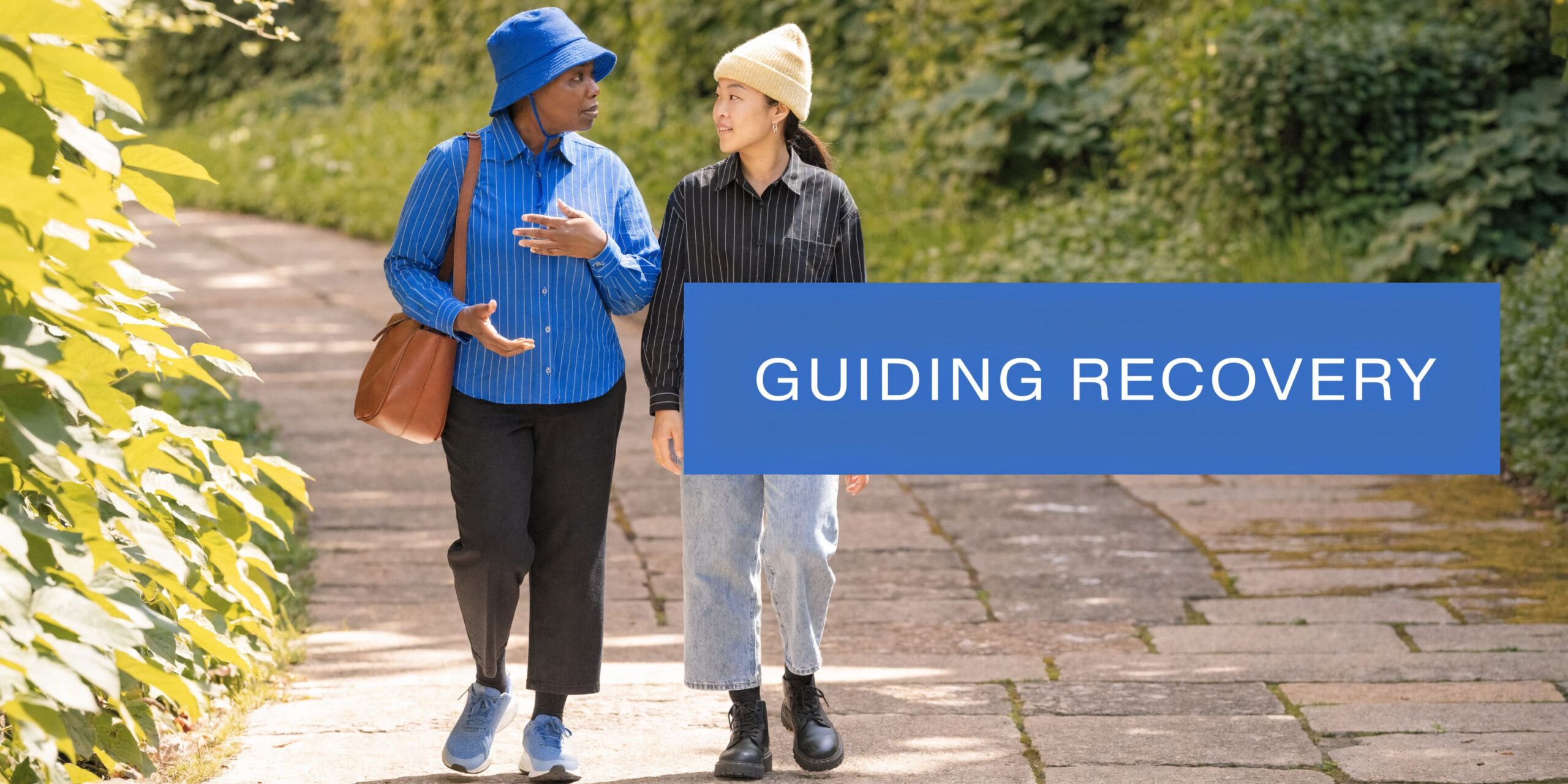 A sponsor walks outdoors with a person in recovery while having a supportive and meaningful conversation.