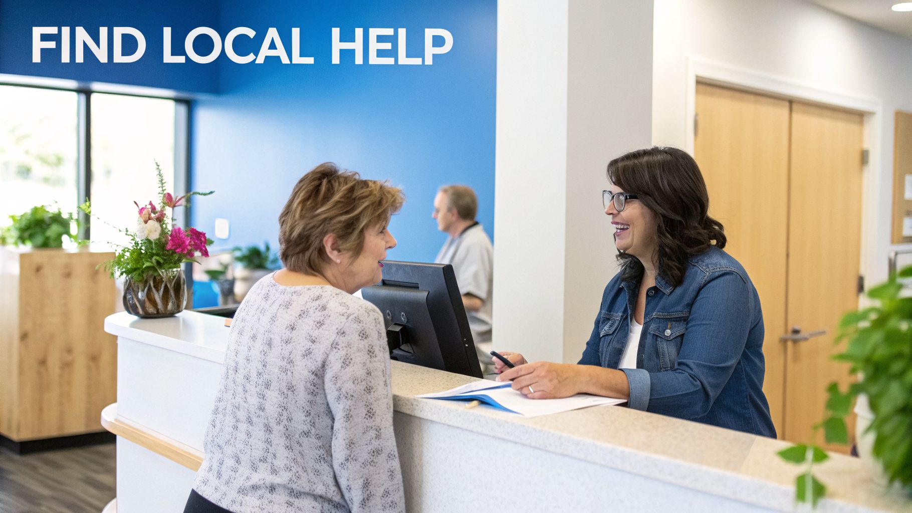 A friendly receptionist helps a woman at a modern office desk with "FIND LOCAL HELP" on the wall.