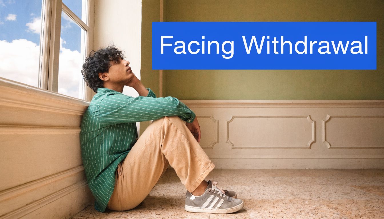 A pensive young man with curly hair sitting on the floor by a bright window, appearing contemplative.