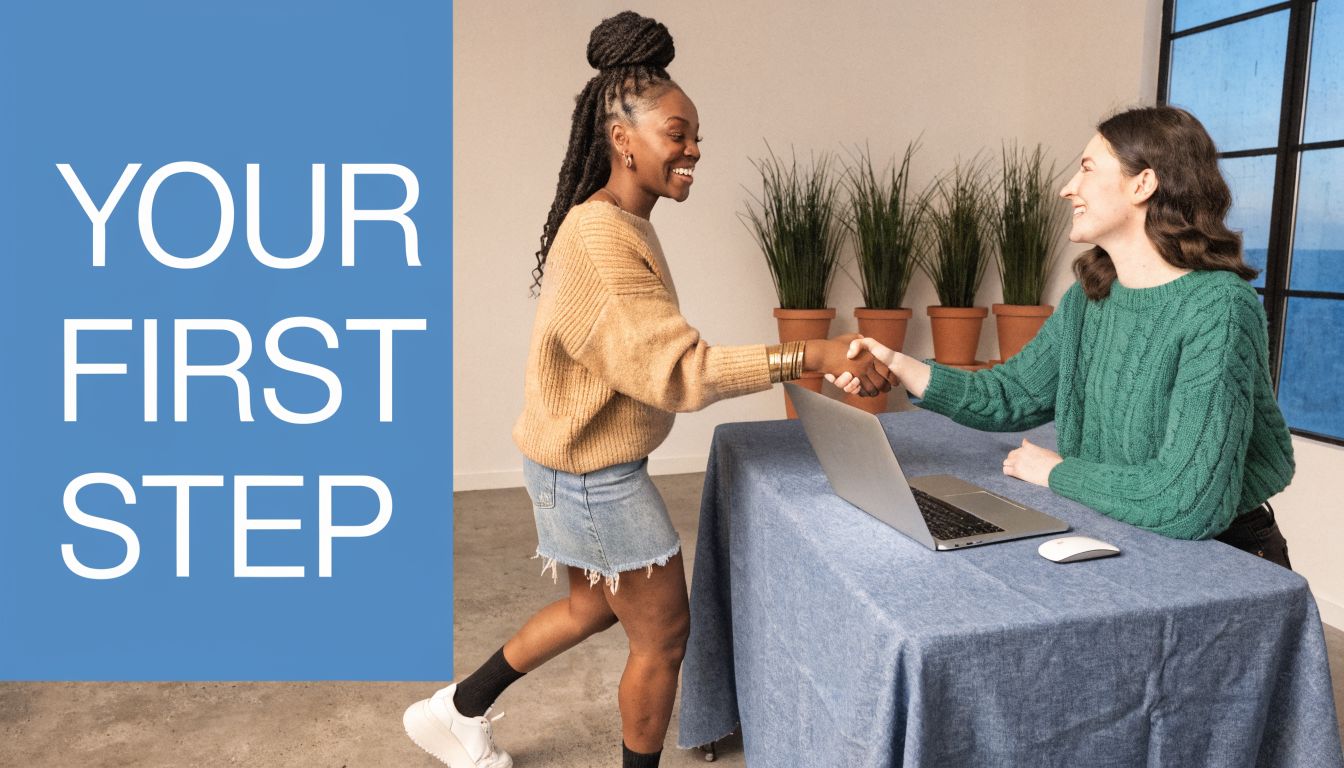 Two women smiling and shaking hands across a table with a laptop, representing a professional new beginning.